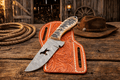 Cowboy Hunting Belt Knife – 4" Damascus Steel Sheep Horn Handle - SHAM KNIVESCowboy KnifeSHAM KNIVESCowboy hunting belt knife with 4 inch Damascus steel blade, sheep horn handle and dog wire cut blade with tooled leather sheath on rustic wooden table in western barn setting