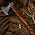 Handmade Damascus steel axe with carved rosewood handle on rustic wooden table.