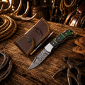 Handmade Damascus folding pocket knife with green Pakka wood handle with leather sheath.
